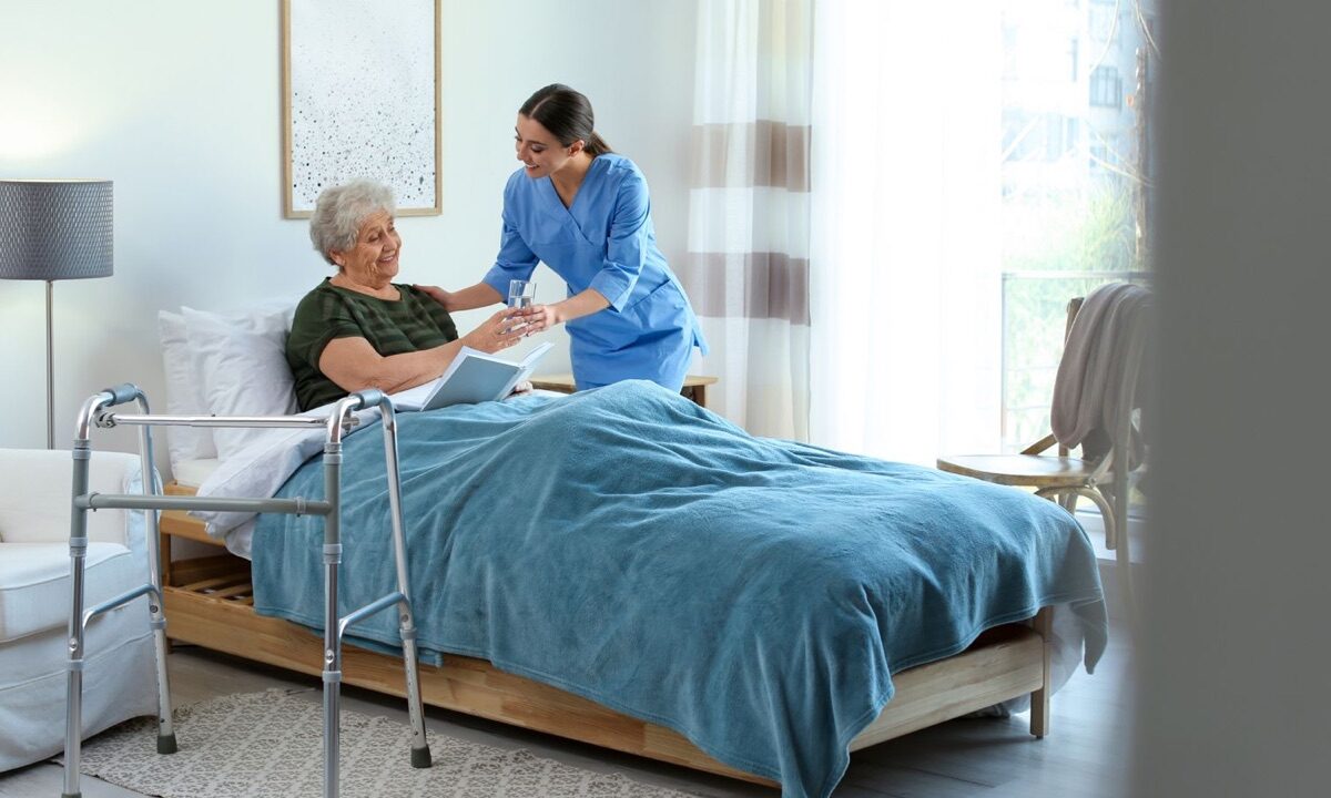 Caregiver bringing a glass of water to an older woman resting at home