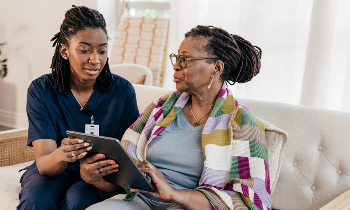 Caregiver reviewing a care plan on a tablet with an older adult at home